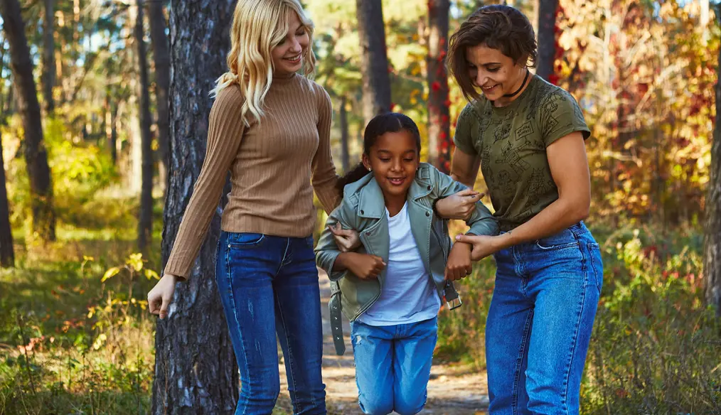 2 women playing with a girl in the woods