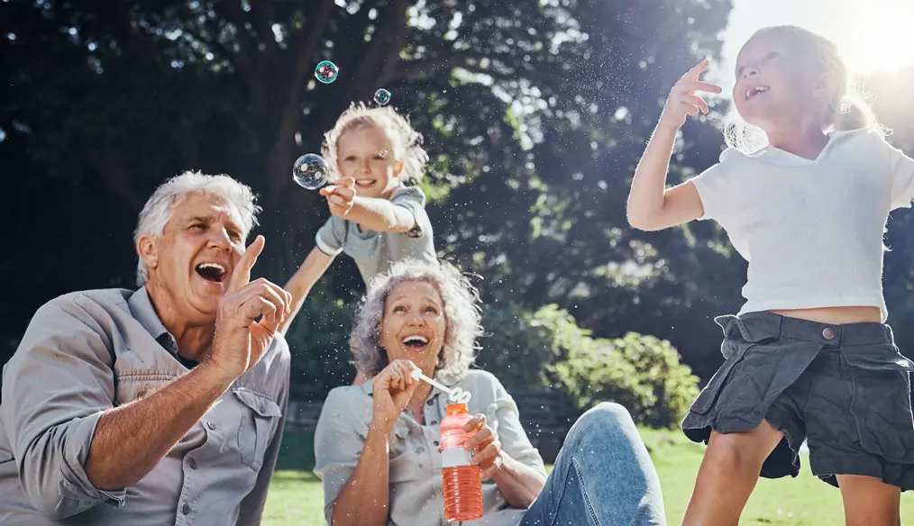 Grandparents outside blowing bubbles with grandchildren