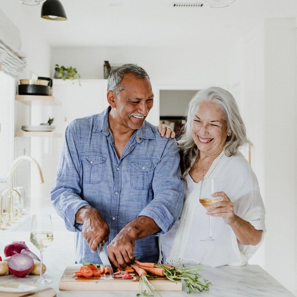 older man and woman in a kitchen chopping vegetables